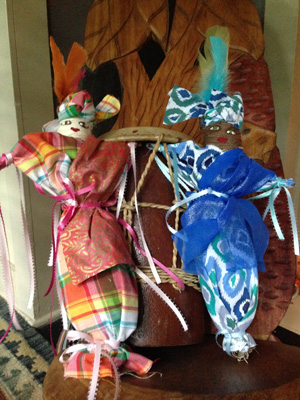 Two Congo Square Voodoo dolls resting on a beautiful wooden chair