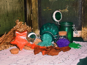 Bottles of voodoo magik bath salts on a table with dried herbs