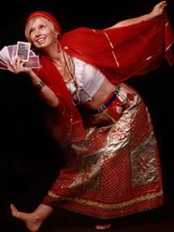 Voodoo Priestess Severina in a red skirt and head scraf holding tarot cards